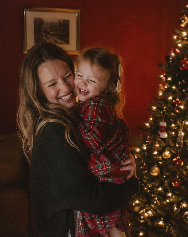 Mãe e filha abraçadas diante da árvore